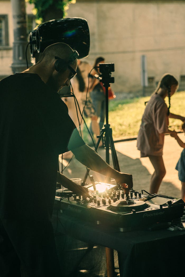 DJ mixing music at an outdoor summer party in Lwiw, Ukraine with people dancing in the background.
