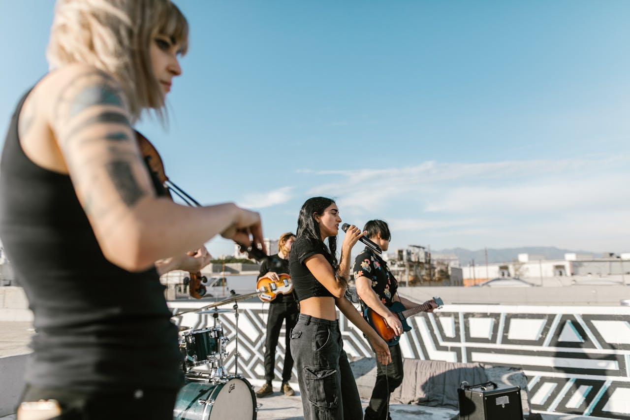 A band performing music on a rooftop with a female vocalist and musicians under a clear blue sky.