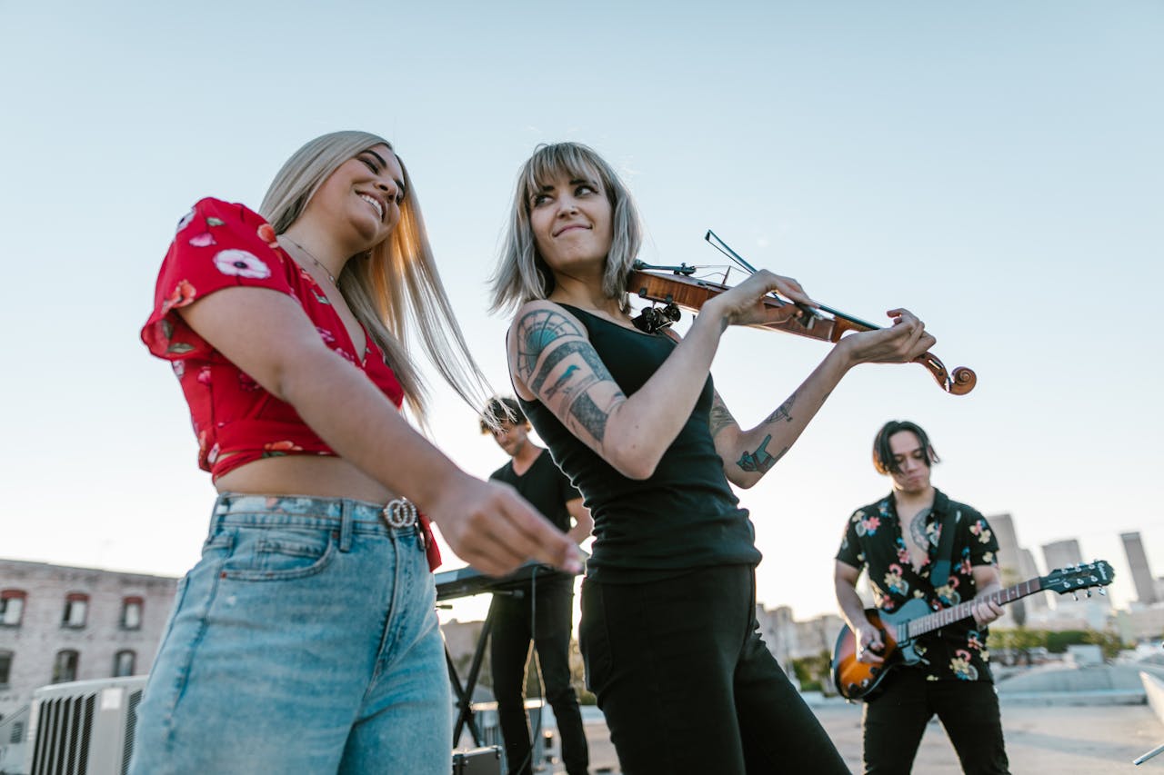 A vibrant music band performing on a rooftop during the day with a violinist and guitarist.