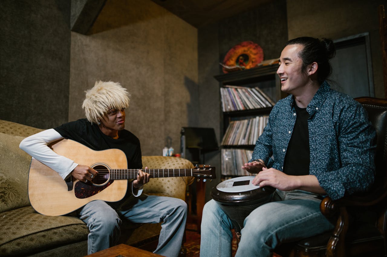 Two musicians having fun playing guitar and drum in a cozy music studio.